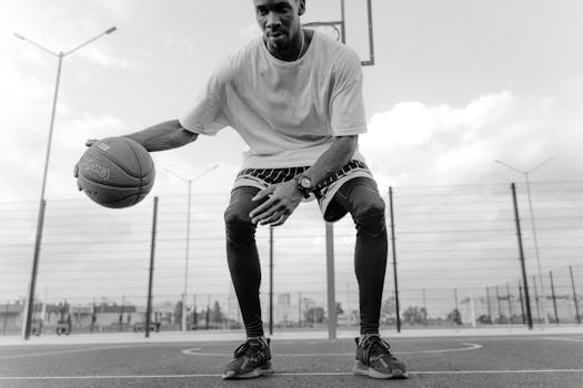 A man skillfully dribbles a basketball on an outdoor court in a captivating black and white setting.