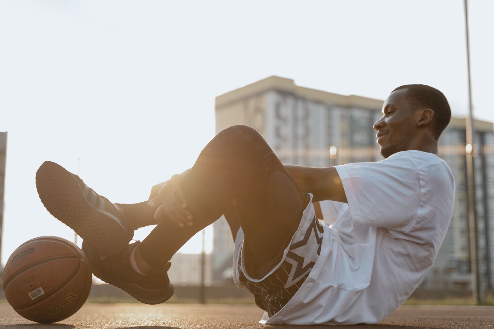 Person tying a running shoe before walking outdoors, with focus on the heel and ankle area