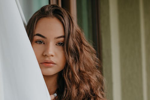 Free Contemplative ethnic woman with makeup near wall Stock Photo