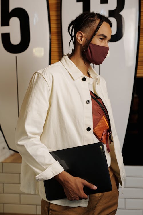 Free A Man Holding a Laptop and Wearing a Face Mask Stock Photo