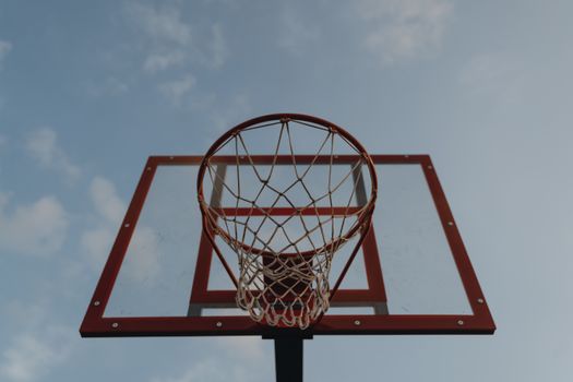 Photo of a basketball hoop with a transparent backboard against a clear blue sky, ideal for sports themes.