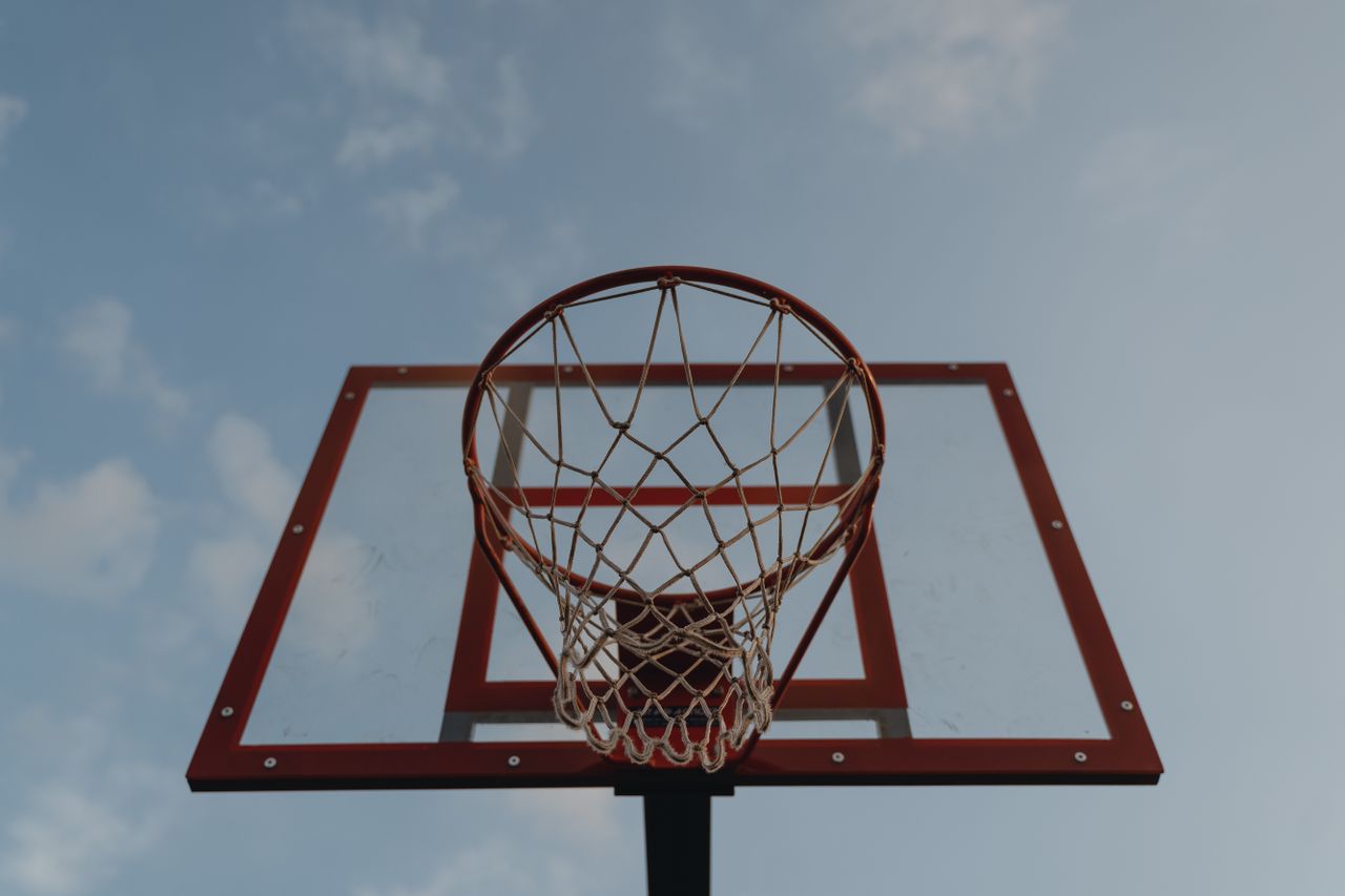 photo of a basketball hoop with a transparent backboard against a clea