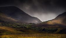 Green Grass Field Near Mountain Under Cloudy Sky
