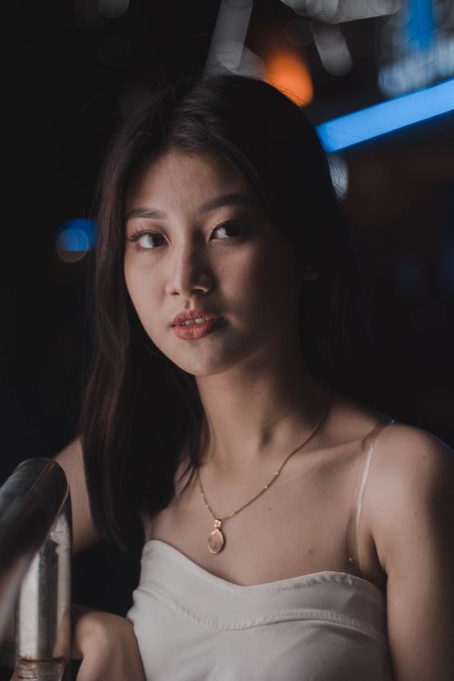 Free Portrait of a young woman with soft lighting and urban night ambiance. Stock Photo