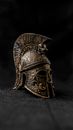 Ancient Greek helmet made of bronze with decorative elements in museum in darkness