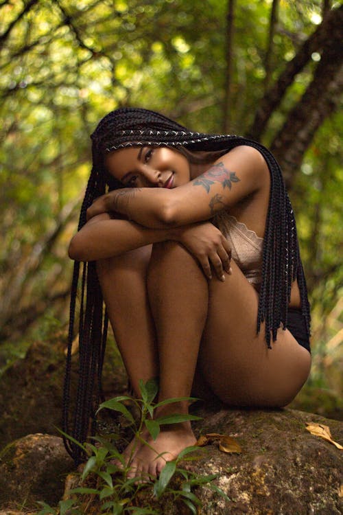 Smiling black woman with long braids resting in forest