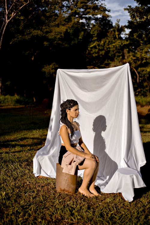 Calm woman sitting on stump against white cloth