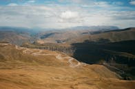 Wavy road in mountains under blue cloudy sky