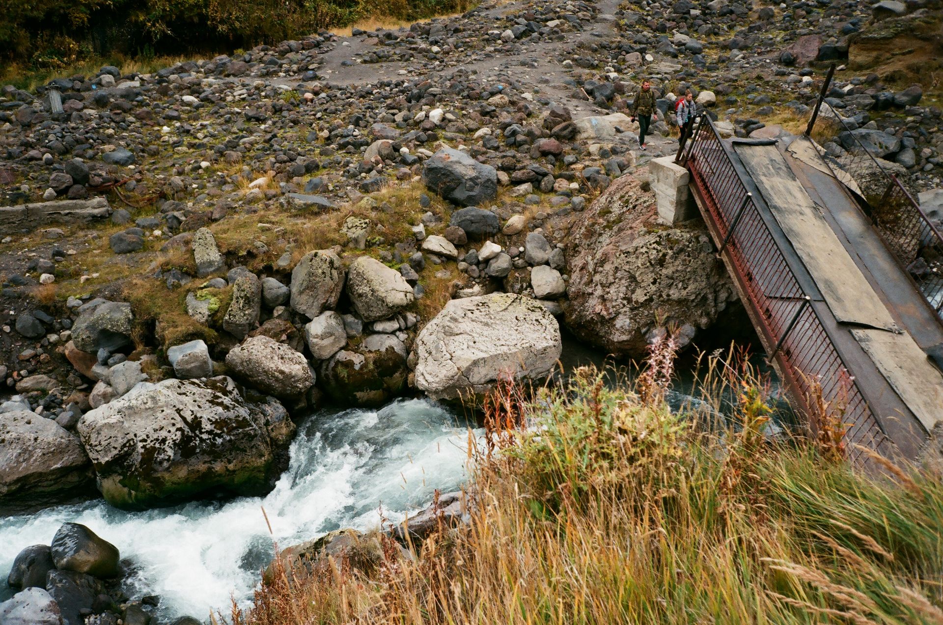 A breathtaking view of a mountain stream flowing under a rustic bridge, perfect for outdoor adventures.