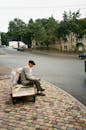 Unrecognizable senior man resting on old garden cart near road