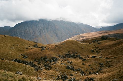 Free Amazing landscape of rocky mountain covered with dry grass in picturesque valley against cloudy sky Stock Photo