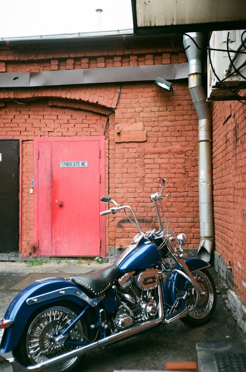 Vintage shiny motorcycle with chrome elements parked on street near aged brick building in daytime