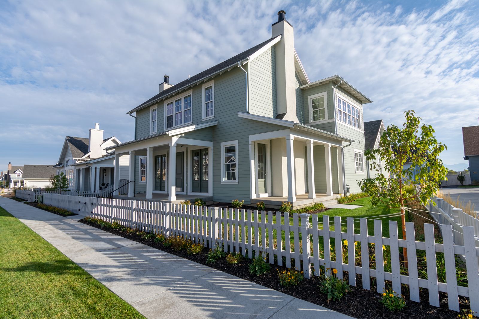 Suburban house behind a white picket fence under clear skies — photo by Get Lost Mike on Pexels