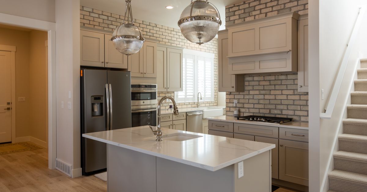 Modern kitchen featuring brick accent, sleek appliances, and stylish lighting for a chic look.