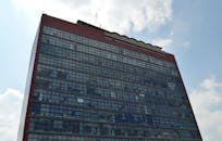 低角度视角下，现代玻璃立面建筑映衬在多云天空之中