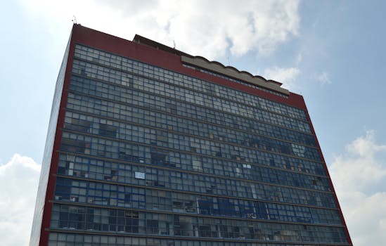 低角度视角下，现代玻璃立面建筑映衬在多云天空之中