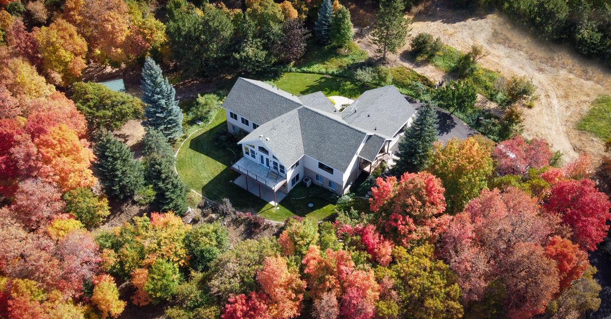 Aerial view of a suburban house surrounded by vibrant autumn trees in Woodland Hills, Utah.
