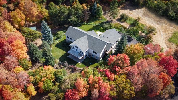 Aerial view of a suburban house surrounded by vibrant autumn trees in Woodland Hills, Utah.