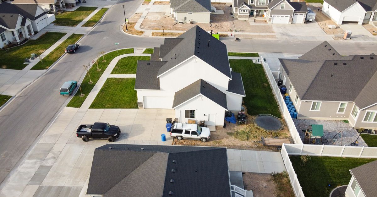 Aerial view of a residential suburban neighborhood in Spanish Fork, Utah with houses and vehicles parked on driveways.