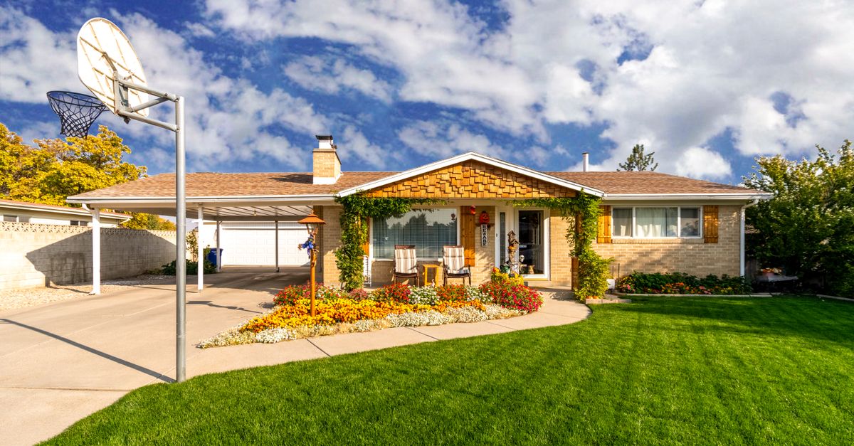 A picturesque suburban home with a green lawn and clear blue sky, captured in daylight.