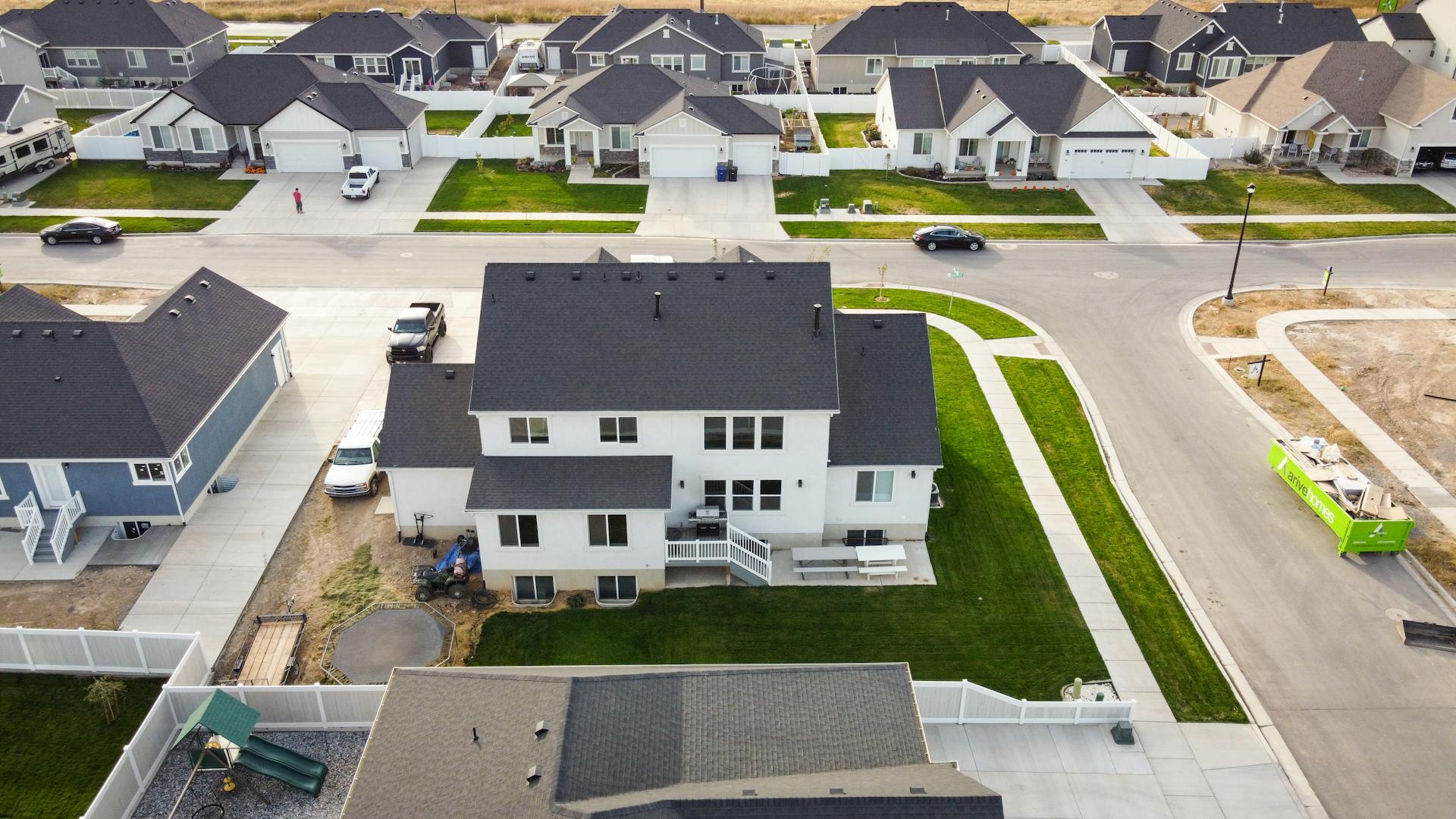 Aerial shot of a residential area in Spanish Fork, Utah, showcasing modern homes and green lawns.