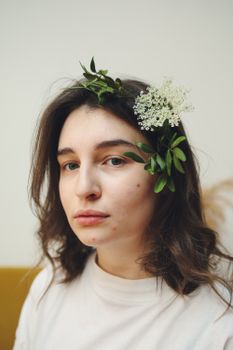 A serene portrait of a woman with natural beauty, showcasing a floral and green leaf hairpiece.