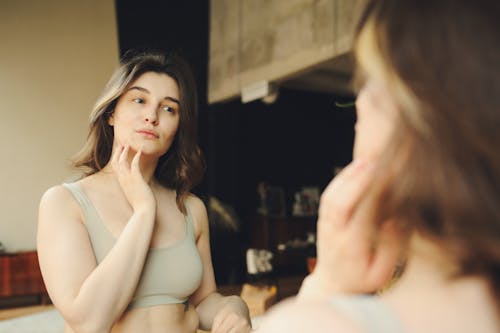 A Woman Looking Her Face in the Mirror