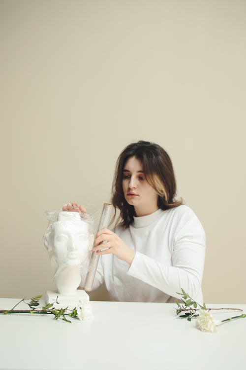 Woman in White Long Sleeve Shirt Sitting at the Table