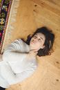 Woman in White Long Sleeve Shirt Lying on Brown Wooden Floor