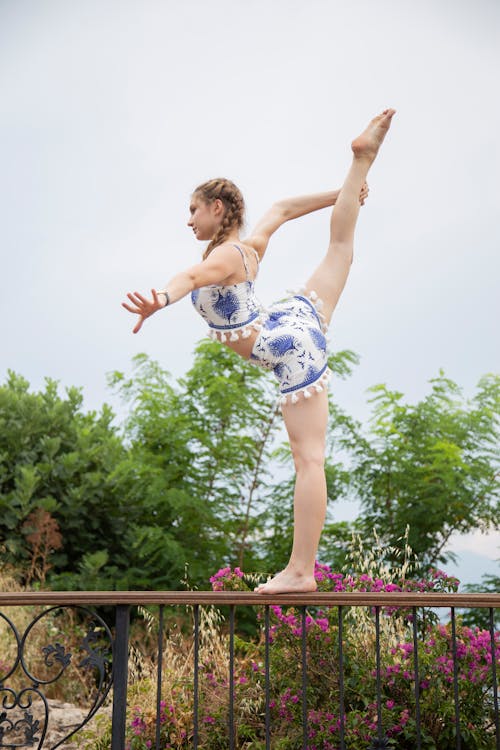 Flexible ballerina standing with raised leg on fence
