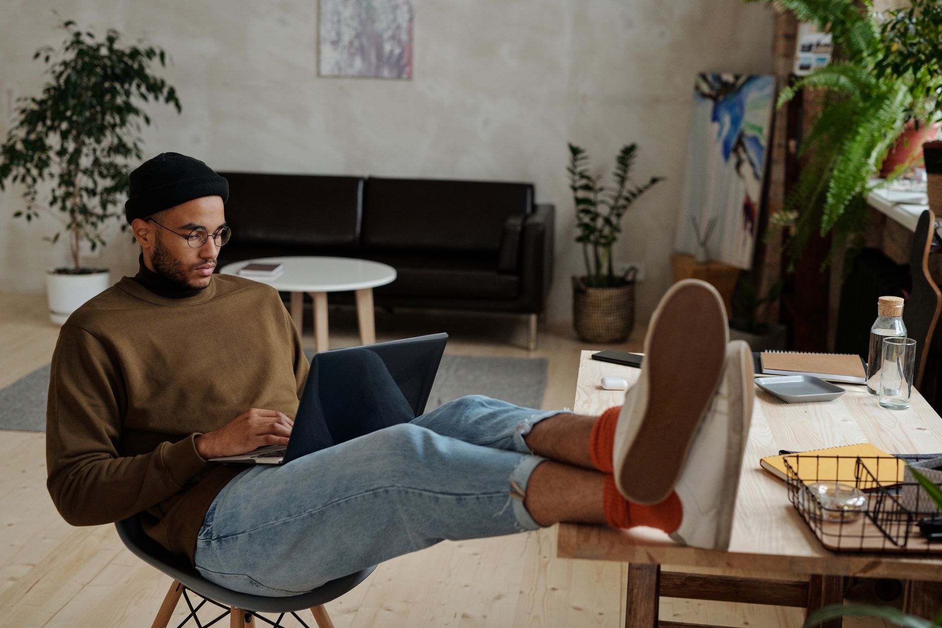 Casually dressed man freelancing with laptop in stylish, plant-filled home office — freelancing marketplace list