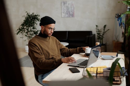 Man in Brown Sweater Using a Laptop
