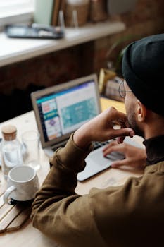 An adult man working on a laptop in a comfortable home setting, indicating remote work or study.