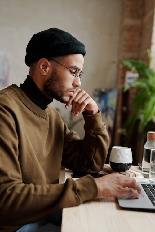 Mann Im Braunen Langarmhemd Und In Der Schwarzen Strickmütze, Die Am Tisch Sitzen