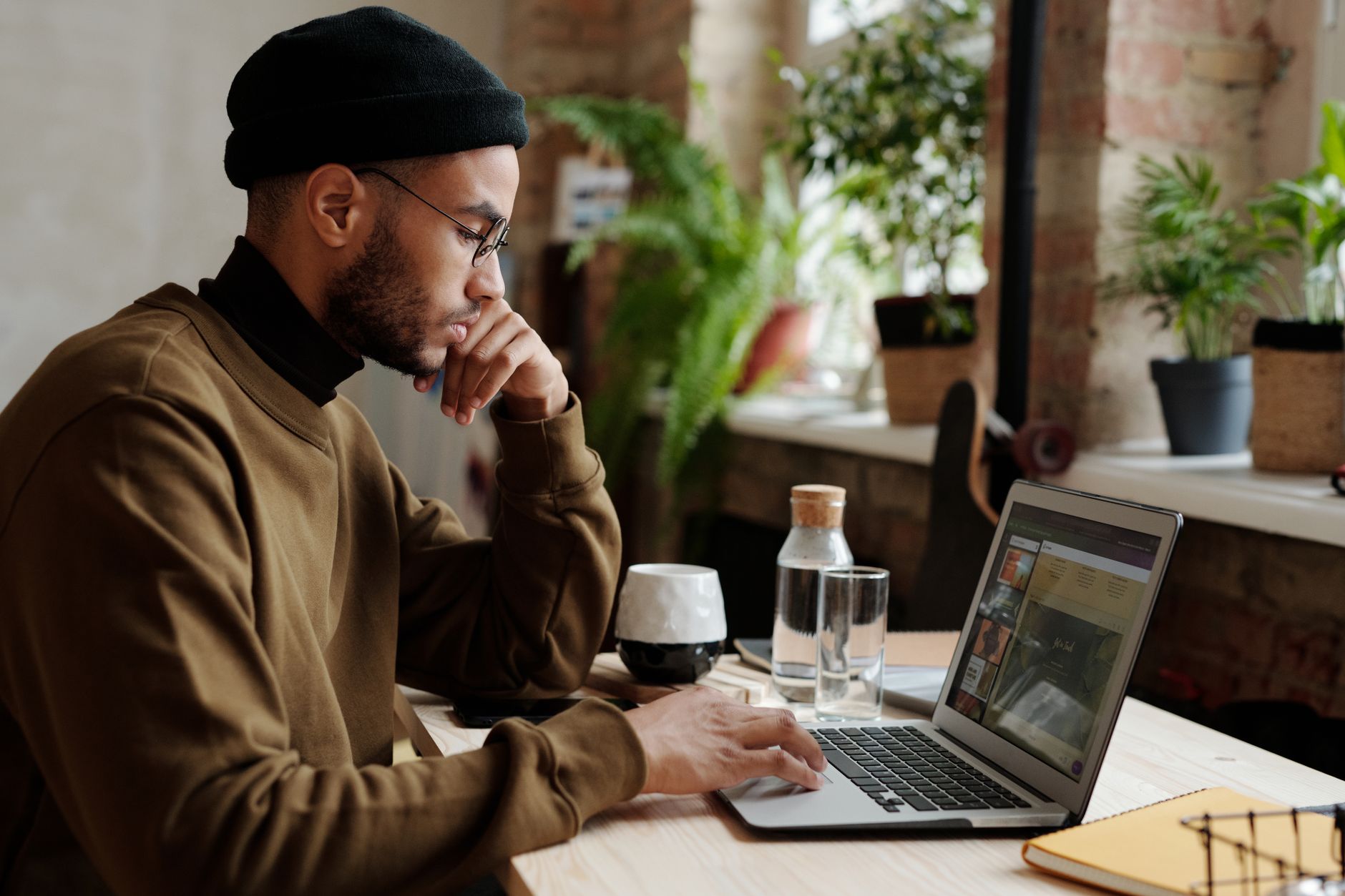 A stylish young man works remotely on his laptop in a cozy indoor workspace — best sites to hire freelancers