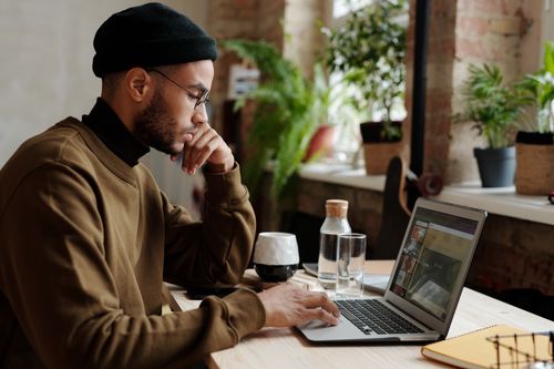 Free A stylish young man works remotely on his laptop in a cozy indoor workspace. Stock Photo