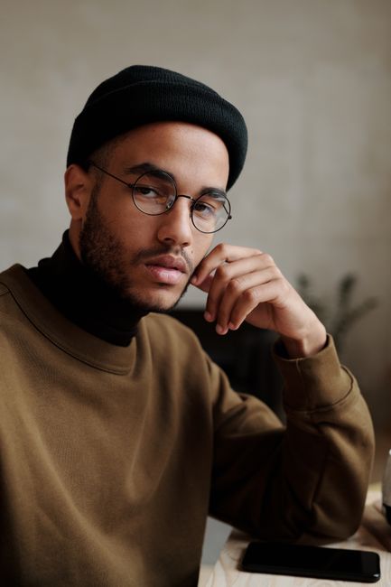 Portrait of a stylish man wearing a beanie and eyeglasses indoors.