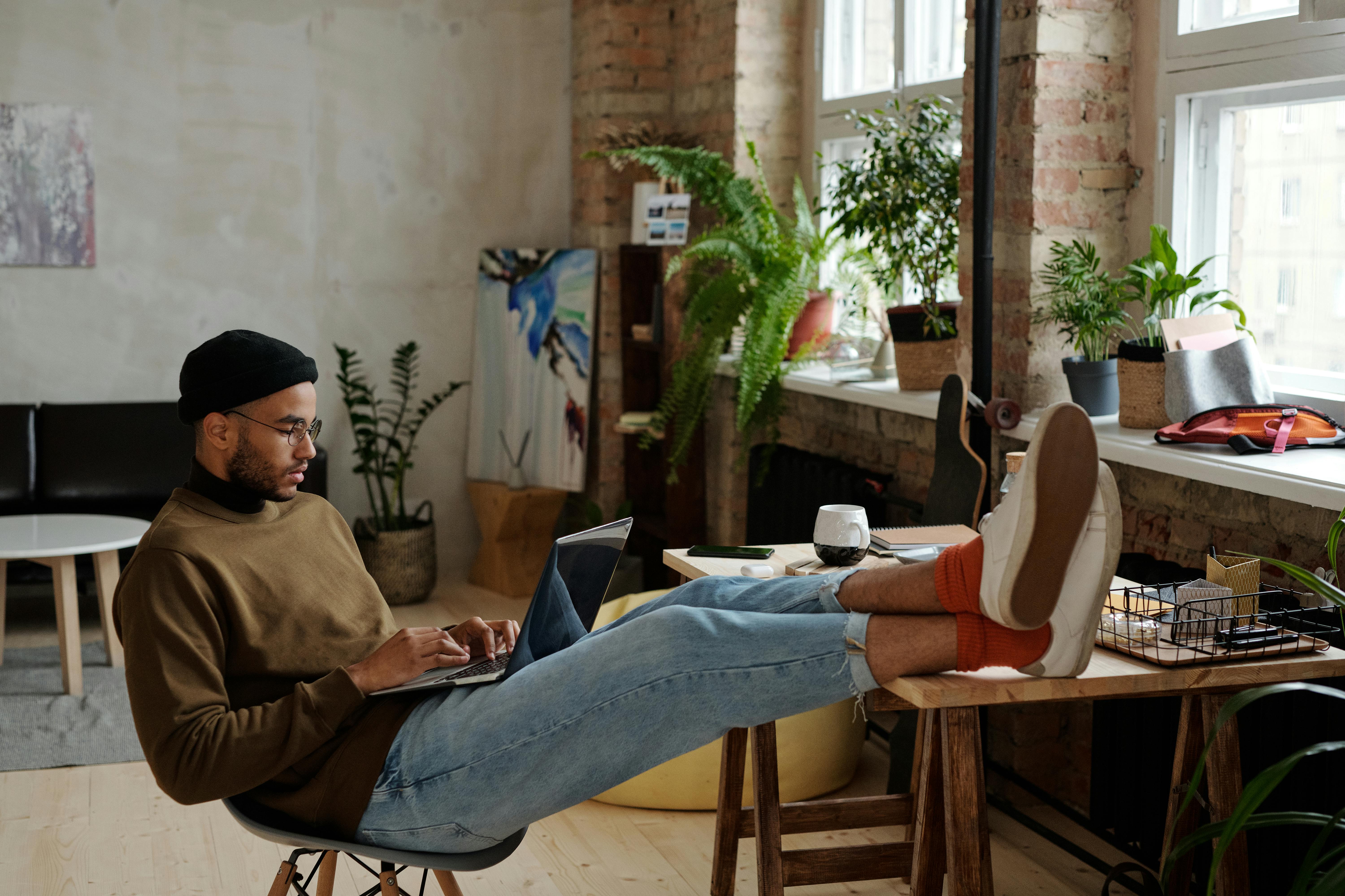 stylish man using a laptop with his legs on the table