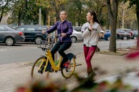 Woman in White Jacket Riding on Bicycle