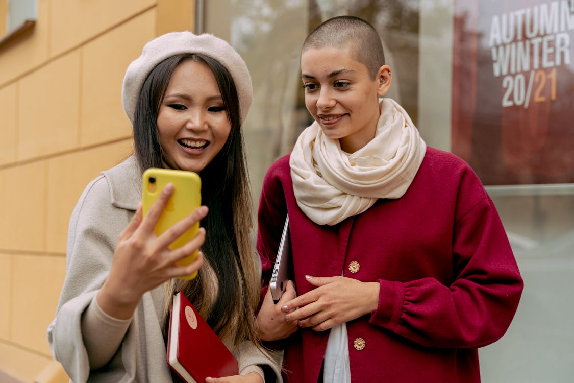 Woman in Red Coat Holding Yellow Smartphone