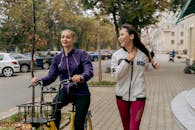 Woman in White Shirt and Red Pants Riding on Black Bicycle