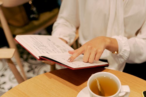 Person in White Long Sleeve Shirt Holding a Notebook 
