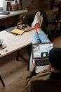 Person in Blue Denim Jeans and White Socks Sitting in Front of Macbook Air