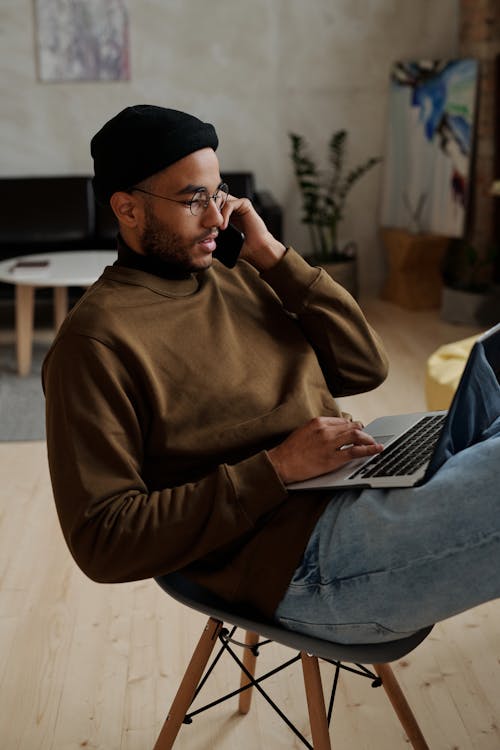 Mann Im Braunen Langarmhemd Und In Den Blauen Jeans, Die Auf Weißer Couch Sitzen