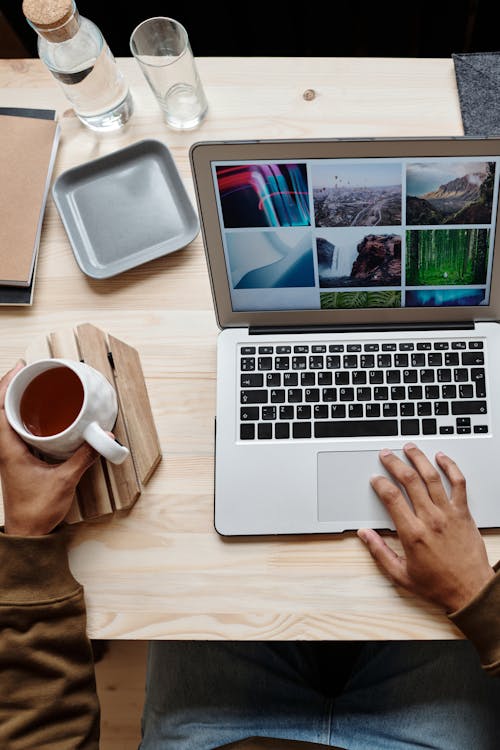 Person using Gray Laptop while holding a Cup of Tea