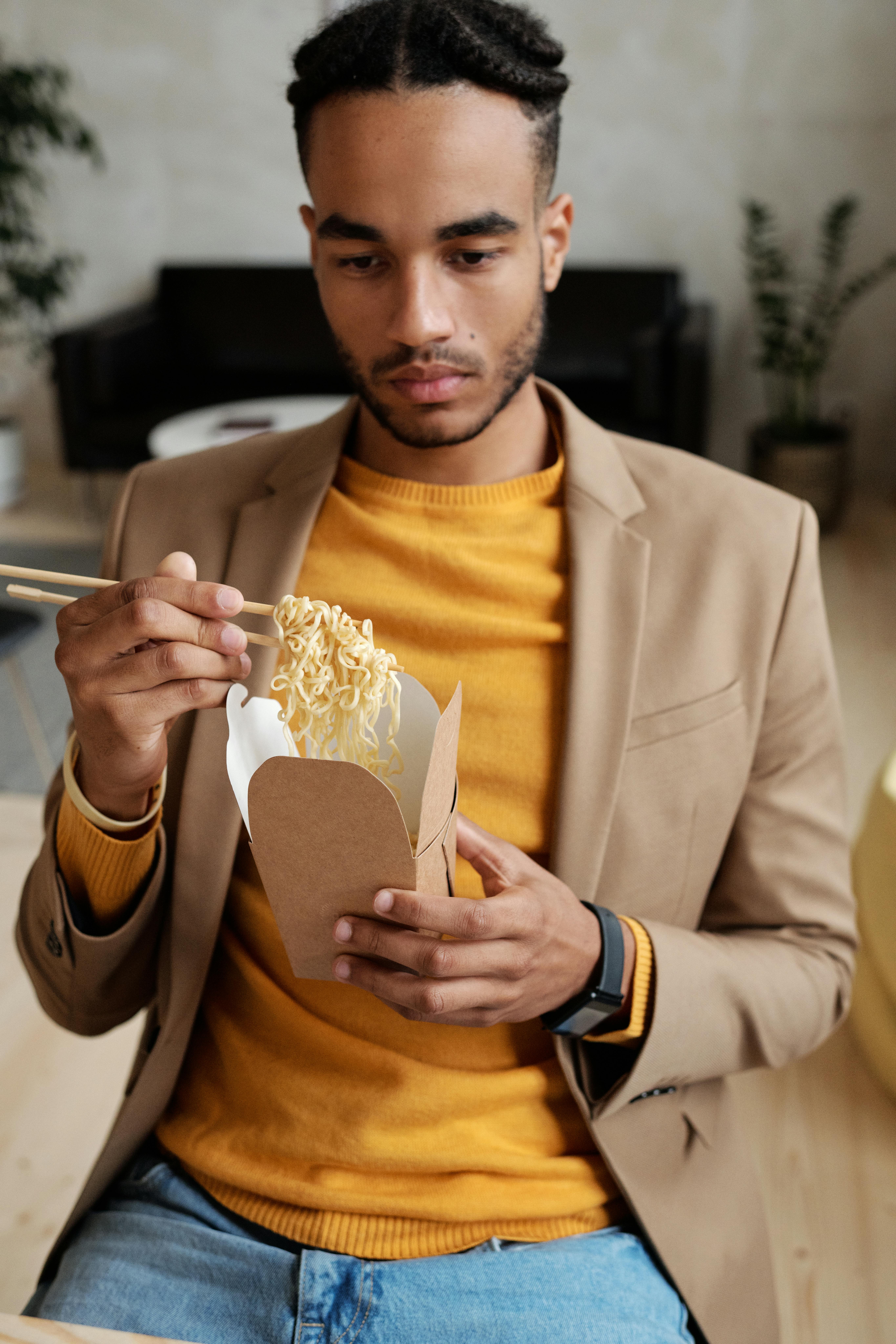 时尚男士用筷子享用亚洲面条，捕捉现代生活方式的瞬间