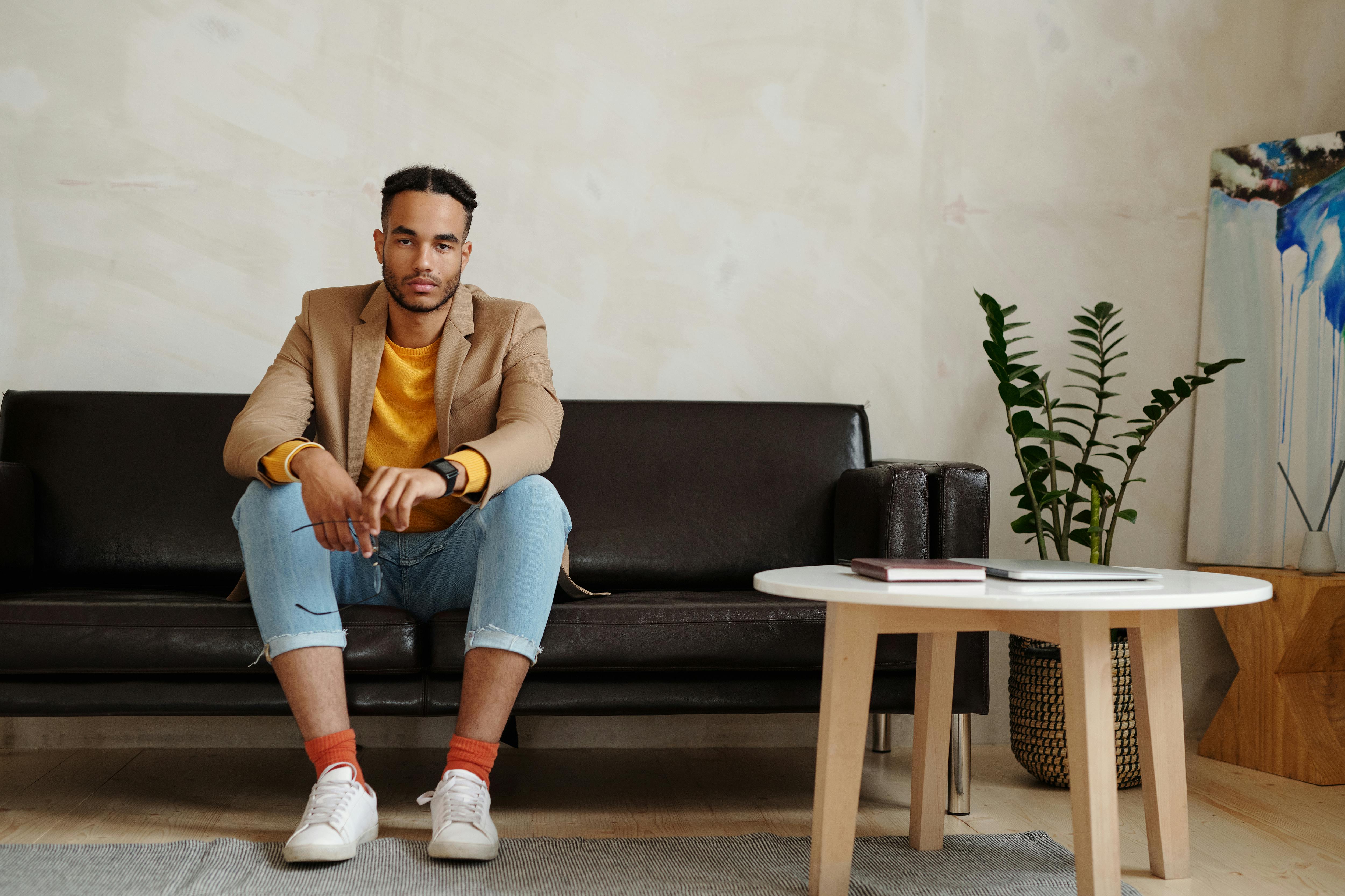 穿着休闲装的时尚年轻人坐在现代室内的沙发上