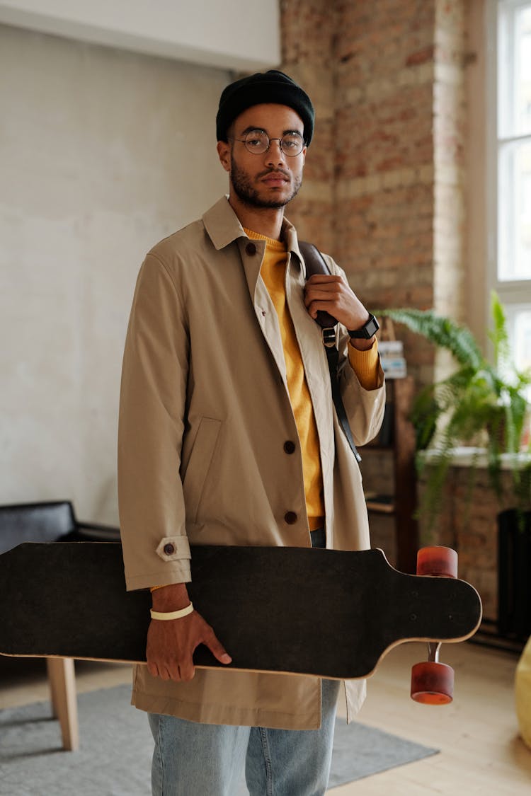 Man In Beige Trench Coat Carrying A Long Board 