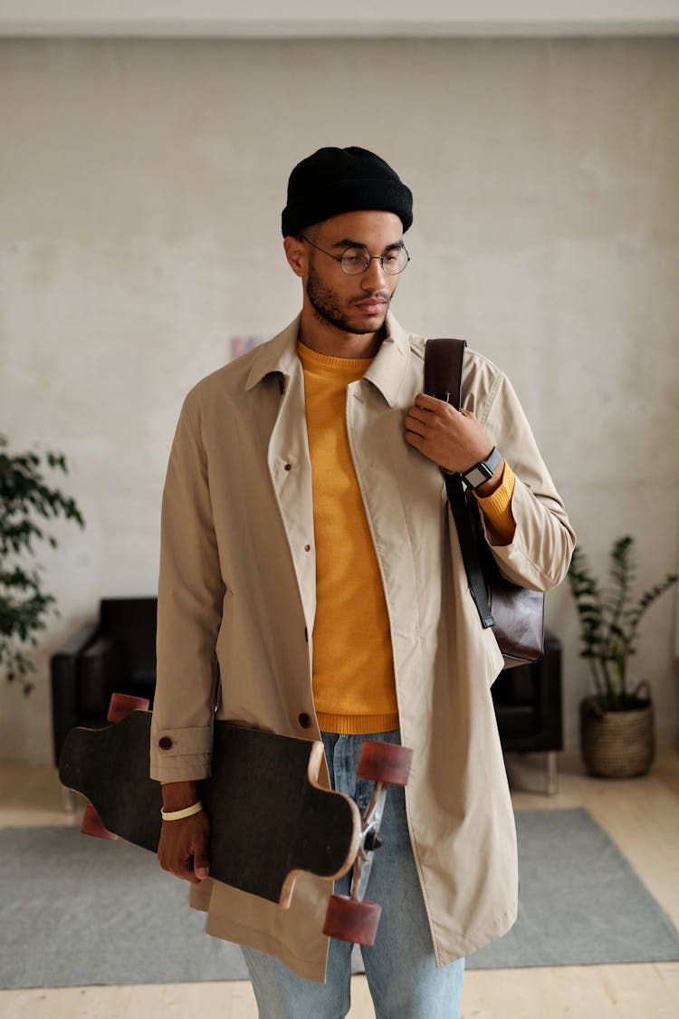 Man In Beige Trench Coat Carrying A Long Board