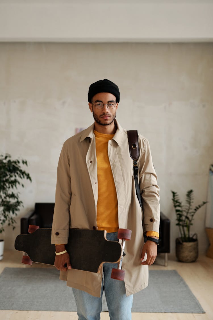 Man In Beige Trench Coat Carrying A Long Board